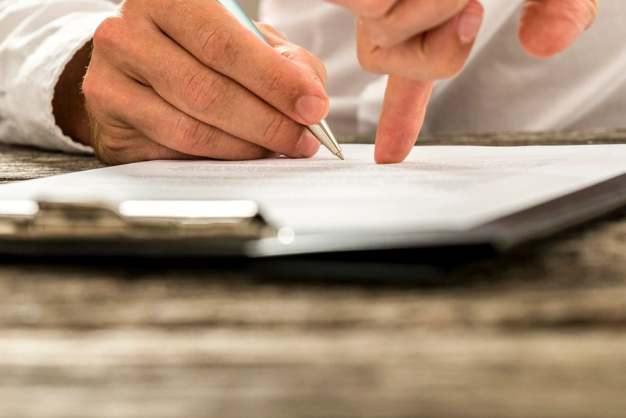 A person writing on paper with a pen.